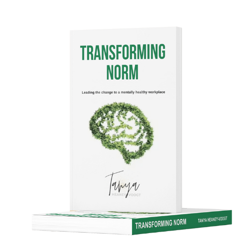 Book titled "Transforming Norm" by Tanya Heaney-Voogt, featuring a brain-shaped tree on the cover and the subtitle about leading healthy workplace change.